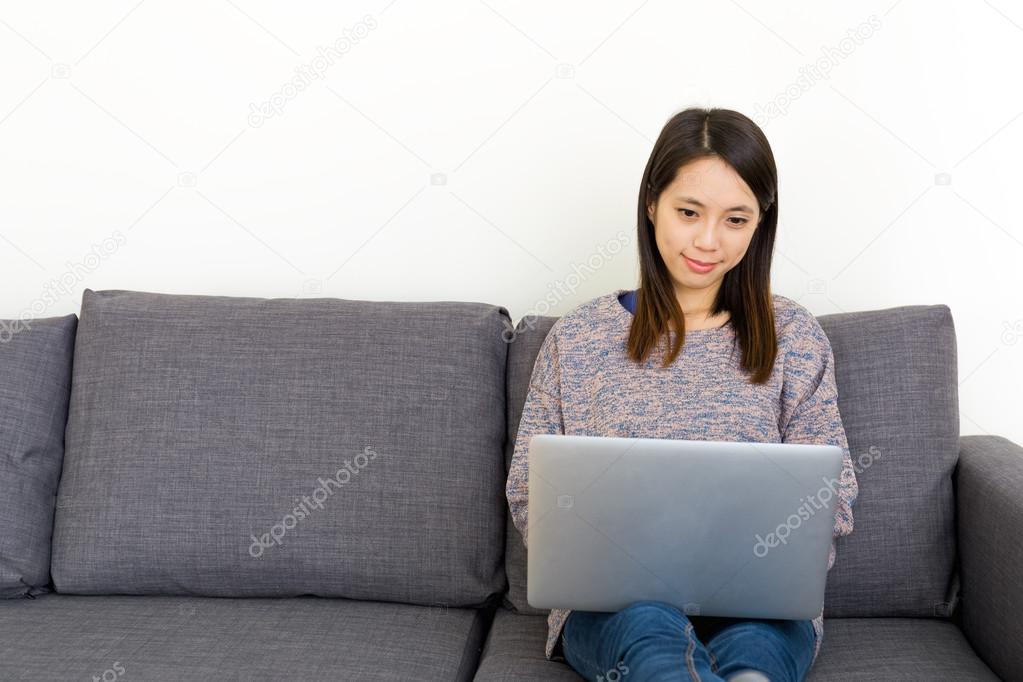 Asian woman using laptop in living room