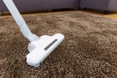 oturma odasında elektrikli süpürge ile kahverengi halı