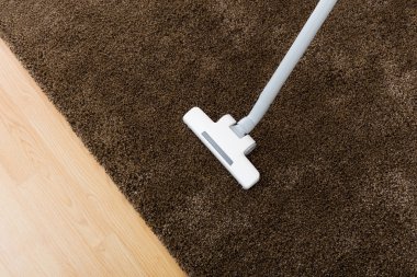oturma odasında elektrikli süpürge ile kahverengi halı