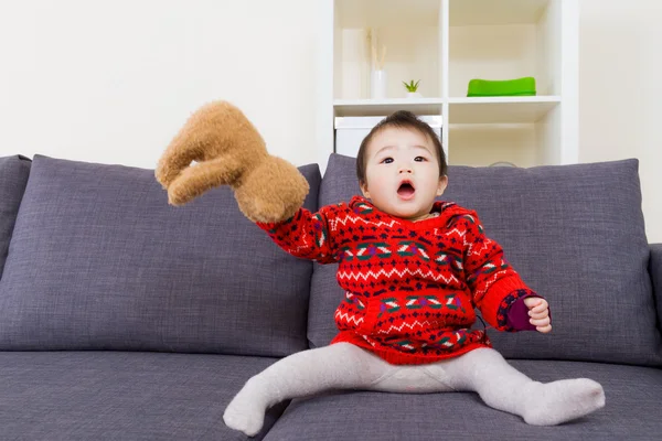 Asiatiska liten flicka spela doll björnen på soffa — Stockfoto