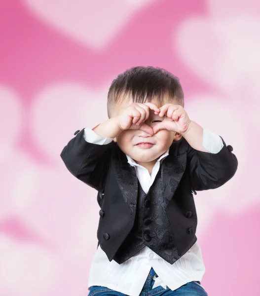 Jongen handjes vertonen tekenen van hart met de roze achtergrond — Stockfoto