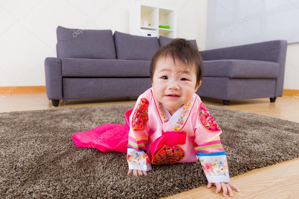 Korean baby with traditional costume crawling on carpet