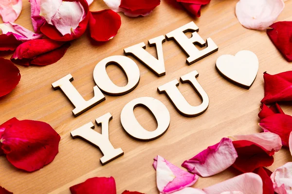 Love You дерев'яні літери з пелюсткою троянд крім того — стокове фото