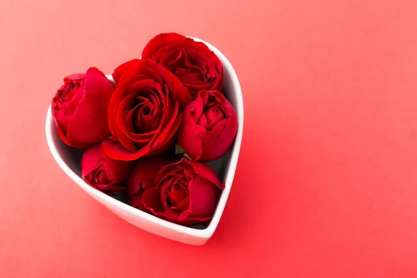 Rose dentro del cuenco con forma de corazón sobre el fondo rojo —  Fotos de Stock