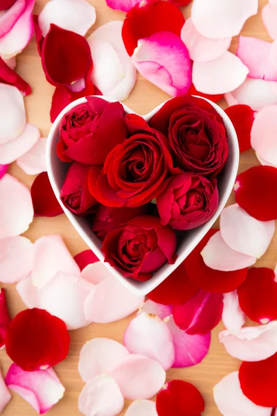 美しい赤いバラ花びらの横にある心臓形状のボウル内 — ストック写真