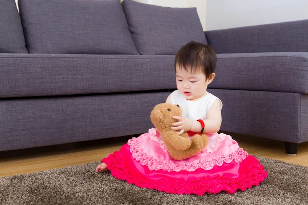 Petite fille jouant poupée et assise sur le tapis — Photo