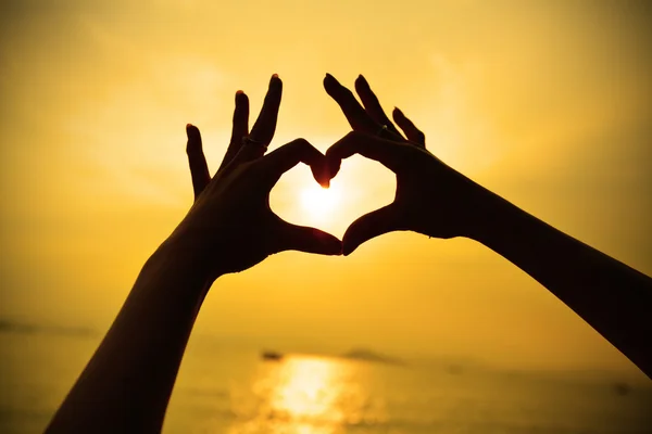 Ręka sylwetka w kształcie serca podczas zachodu słońca — Zdjęcie stockowe