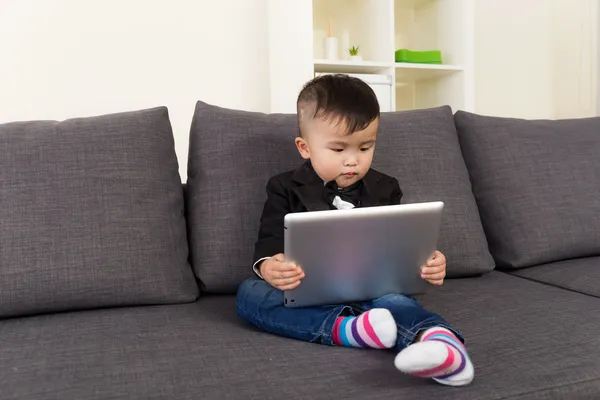 Mały chłopiec za pomocą cyfrowego tabletu i siedzi na kanapie — Zdjęcie stockowe