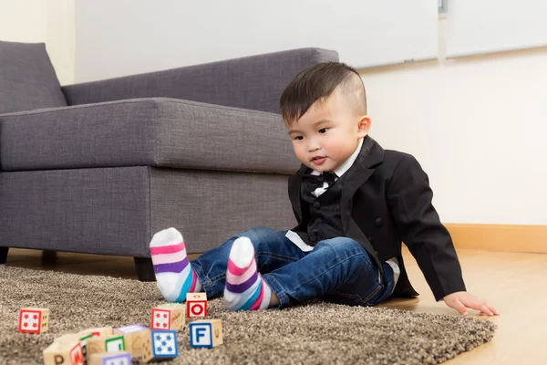 Мальчик играет в игрушечный блок дома — стоковое фото