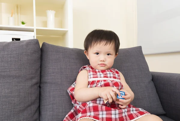 Asiático bebé niña jugar con juguete bloque y sentado en sofá —  Fotos de Stock