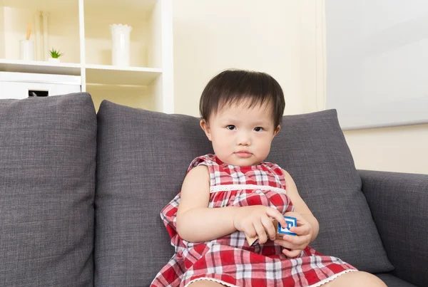 Asiático bebê menina jogar com brinquedo bloco e sentado no sofá — Fotografia de Stock