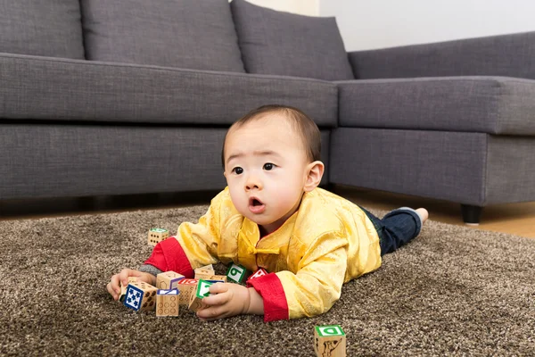 中国小男孩玩玩具块和躺在地毯上 — 图库照片
