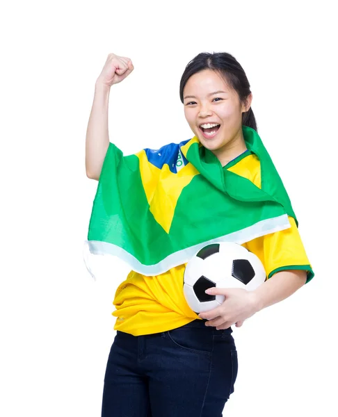 Opgewonden Aziatische vrouw gedrapeerd met Brazilië vlag en bedrijf voetbal — Stockfoto