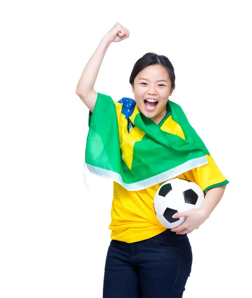 Opgewonden Aziatische vrouw gedrapeerd met Brazilië vlag en bedrijf voetbal — Stockfoto