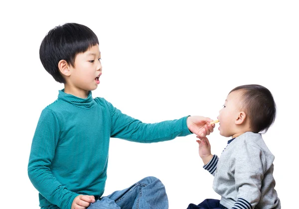 Asiático chico dando galleta a su pequeño hermano Imagen De Stock