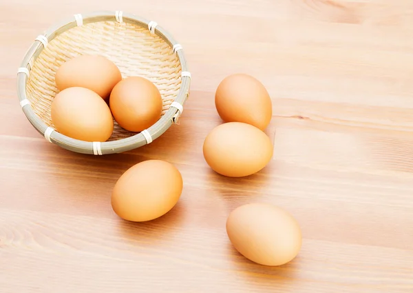 Huevos marrones en cesta sobre textura de madera — Foto de Stock