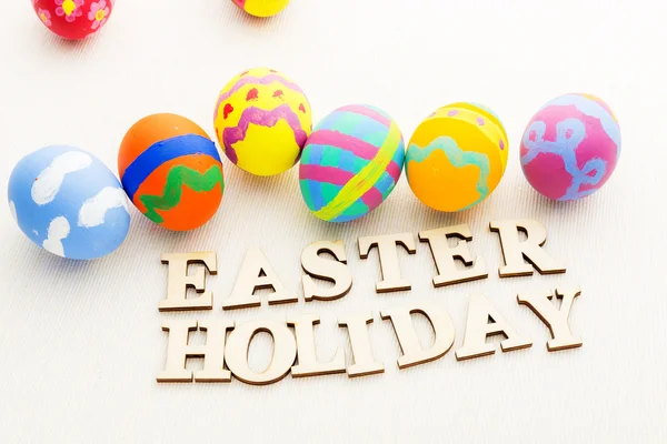 Children painted easter eggs with wooden text — Stock Photo, Image