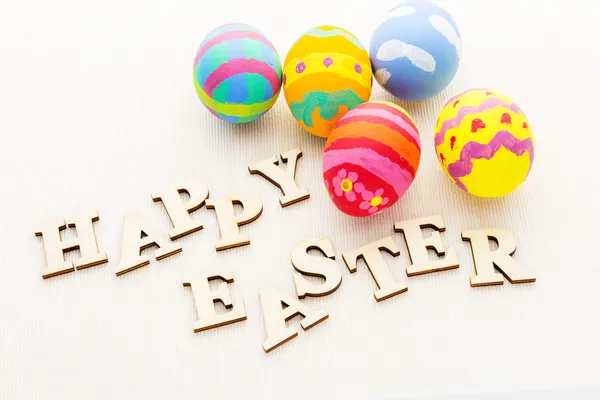 Children painted easter eggs with wooden text — Stock Photo, Image