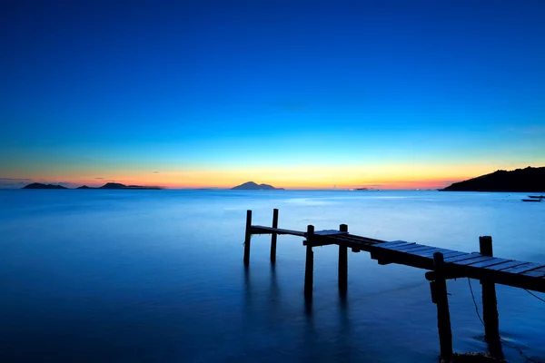 Деревянная пристань с морской накидкой во время захода солнца — стоковое фото