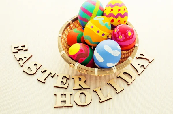 Easter eggs in basket with wooden text — Stock Photo, Image