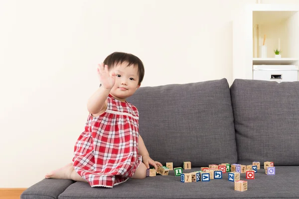 Asiatiska baby flicka spela leksak block och sitter på soffan — Stockfoto