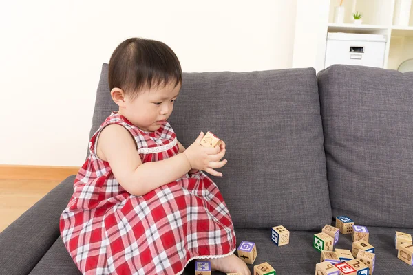 Ásia bebê menina jogar brinquedo blocos e sentado no sofá — Fotografia de Stock