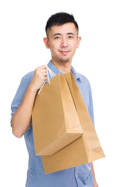 Giovane uomo sorridente che trasporta shopping bag — Foto Stock