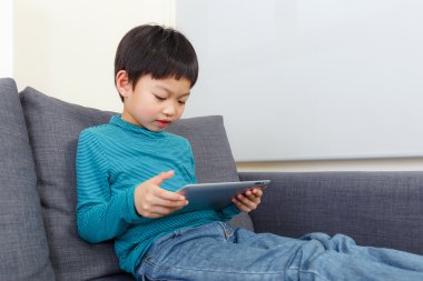 kleine jongen met behulp van Tablet PC en zit op de Bank