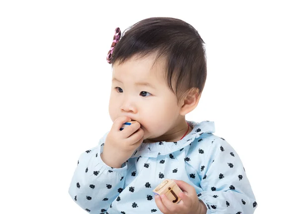 Asia baby girl put wooden toy block into mouth — Stock Photo, Image