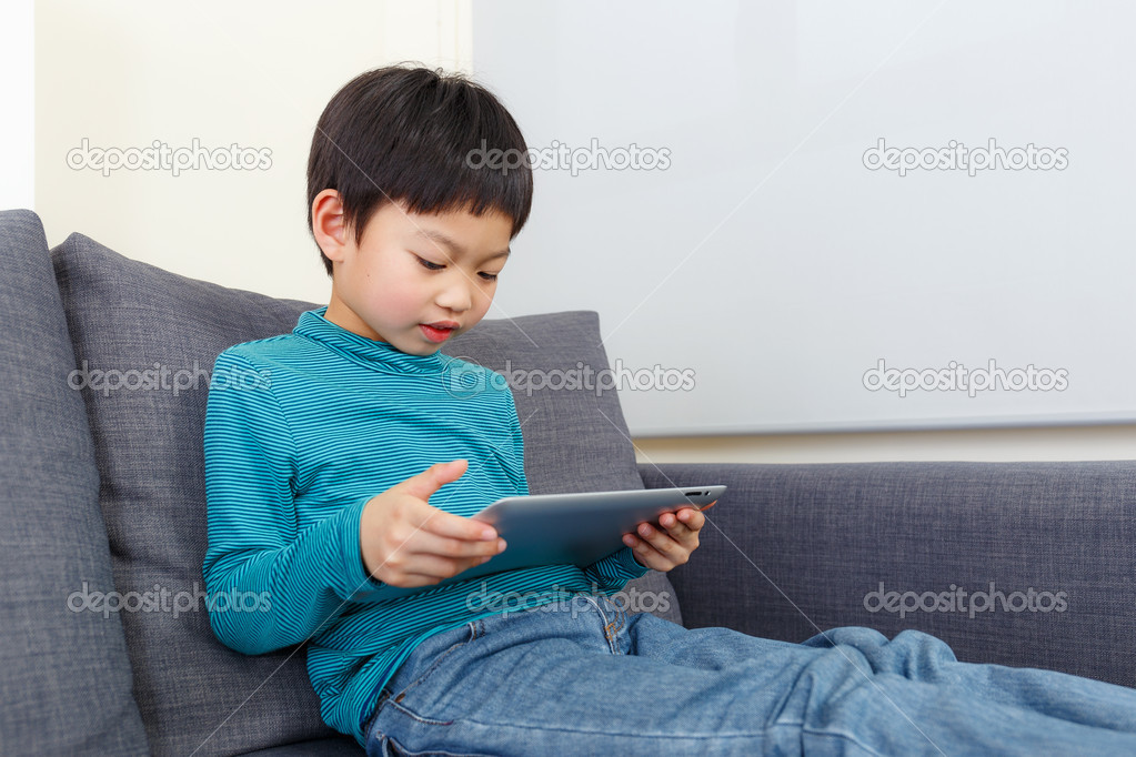 Little boy using tablet and sitting on sofa