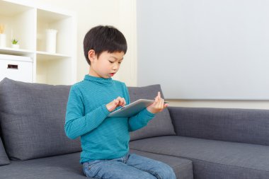Asyalı küçük çocuk evde tablet üzerinde oyun oynama