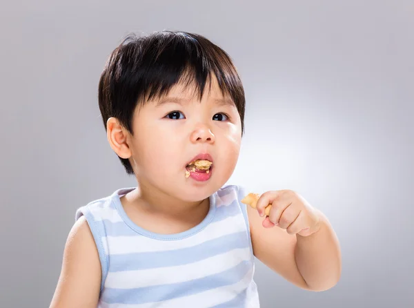 Азиатский мальчик ест печенье — стоковое фото