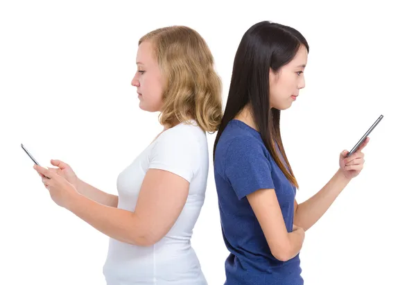 Girl using mobile standing back to back — Stock Photo, Image