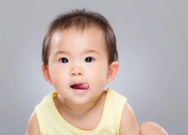 Meisje van de baby tong uitsteekt — Stockfoto