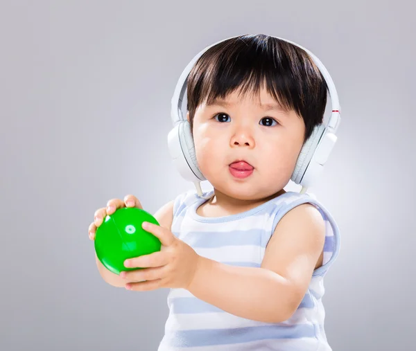 Bayi memegang bola plastik dengan headphone — Stok Foto