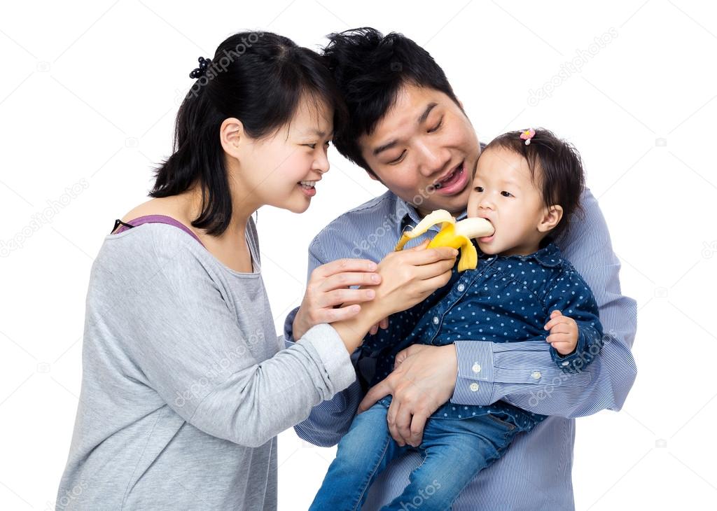 Happy family feeding baby girl with banana