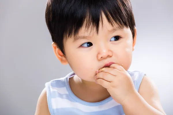 Азиатский мальчик ест печенье — стоковое фото