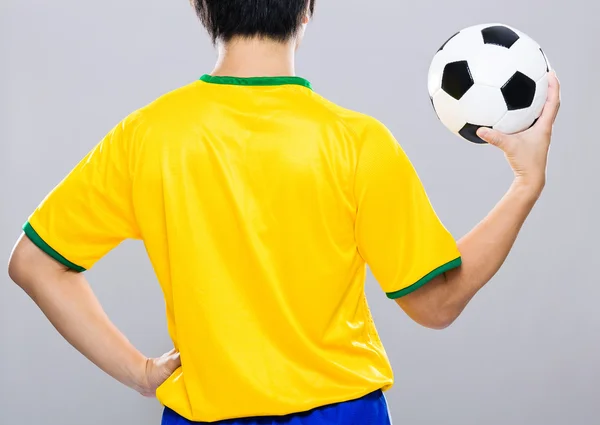 Rückansicht brasilianischer Fußballer hält Fußball hoch — Stockfoto