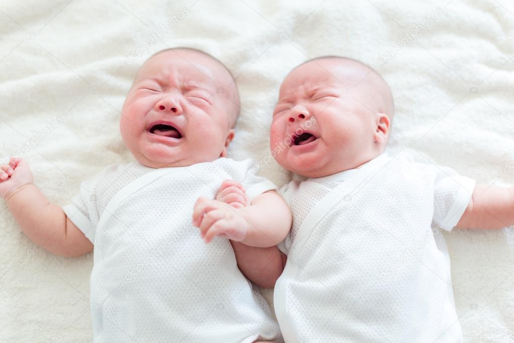 Baby twins cry and lying on bed