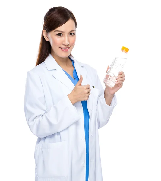 Young doctor thumb up with water bottle isolated — Stock Photo, Image