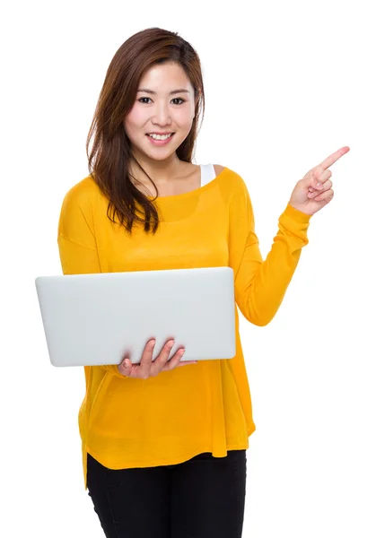 Młoda kobieta korzystanie z komputera przenośnego i punkt palcem na bok — Zdjęcie stockowe
