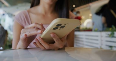 Lokantada kadın akıllı telefonu kullanıyor.