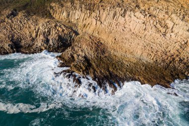 Okyanus dalgaları adada kayalara çarpıyor.