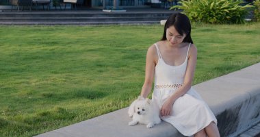 Kadın köpeğini parka getiriyor.