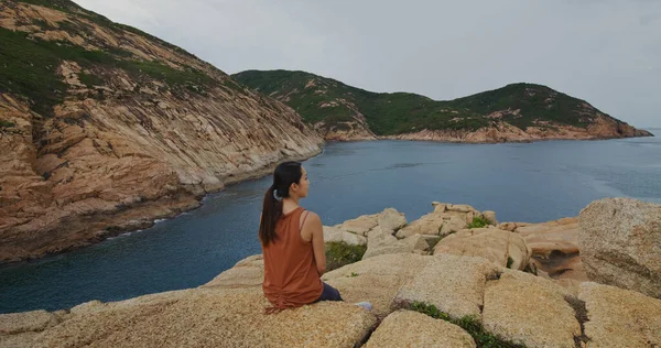 Μια Γυναίκα Κάθεται Στο Βράχο Και Κοιτάζει Θάλασσα — Φωτογραφία Αρχείου