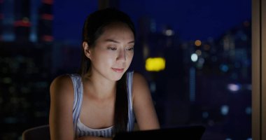 Kadın, gece odada tablet bilgisayar kullanıyor.