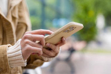 Kadın açık havada cep telefonuna dokunuyor