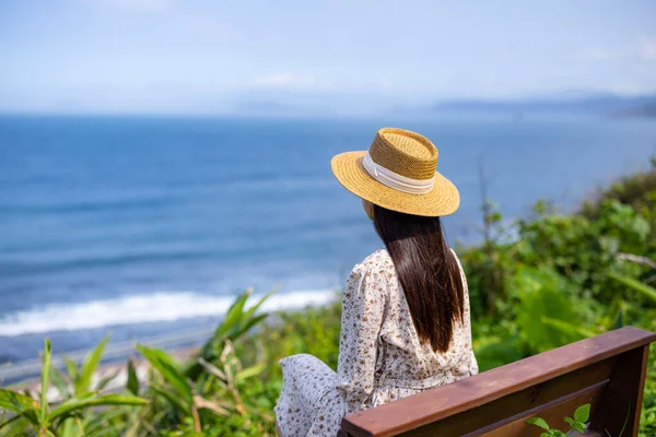 Woman sit on the bench and look at the sea