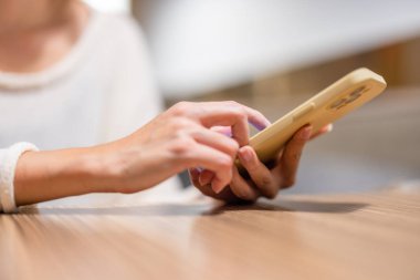 Kadın kahve dükkanında cep telefonu kullanıyor.