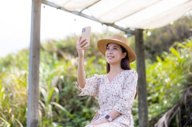 Güzel yeşillik manzarası yerine cep telefonuyla selfie çeken bir kadın.